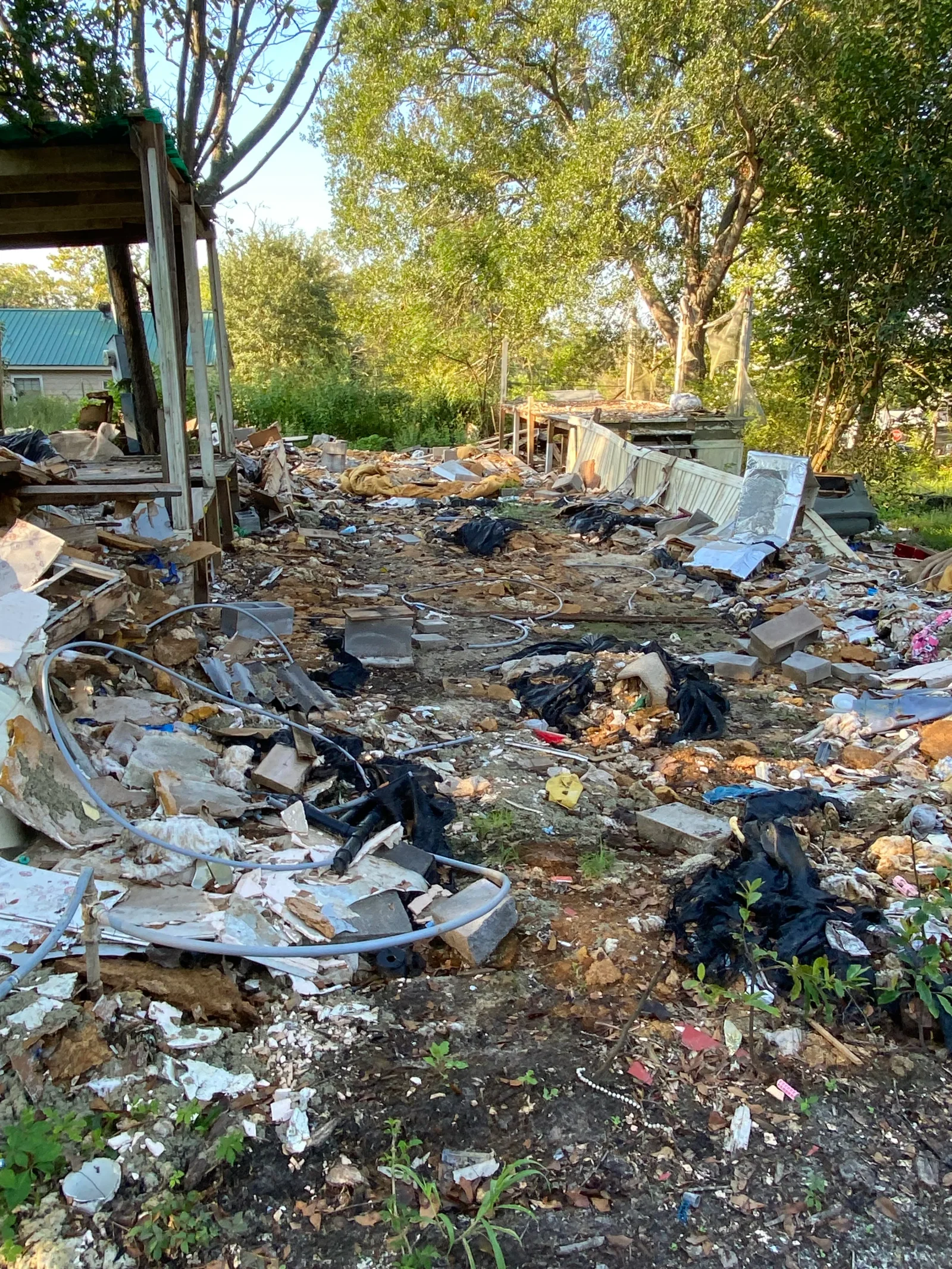 Cleared property with mixed construction debris, metal scraps, and drywall removed from residential site