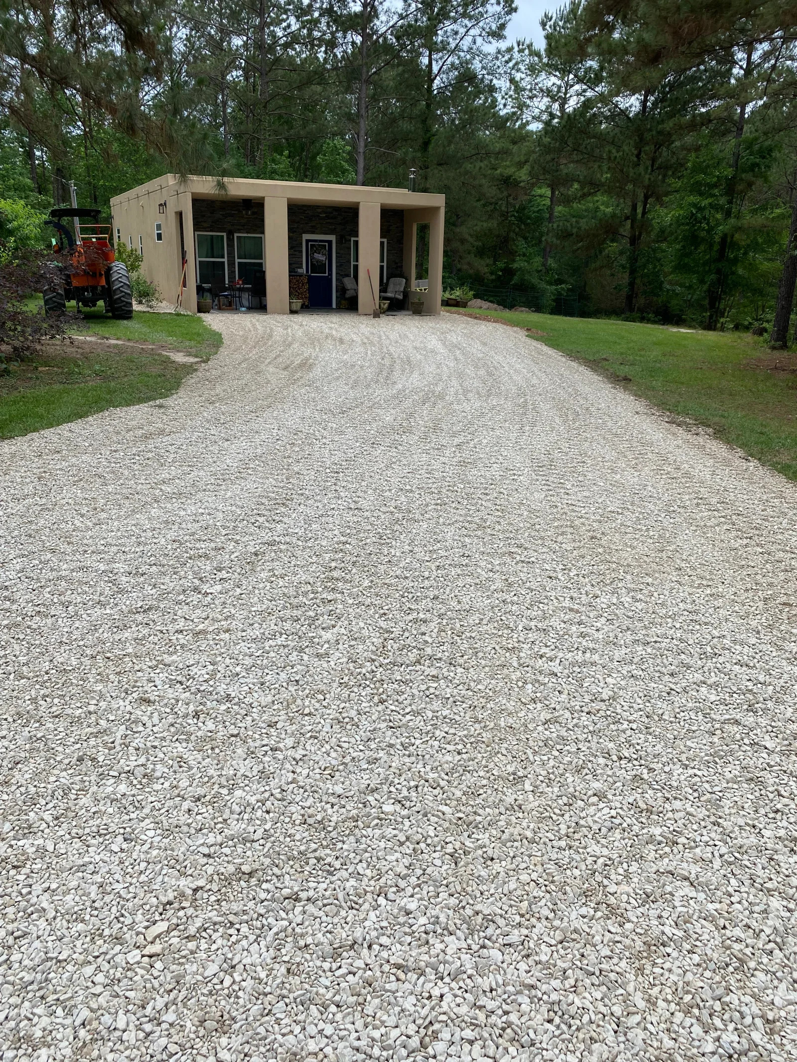 Compacted gravel driveway with crushed stone material leading to tan residential building