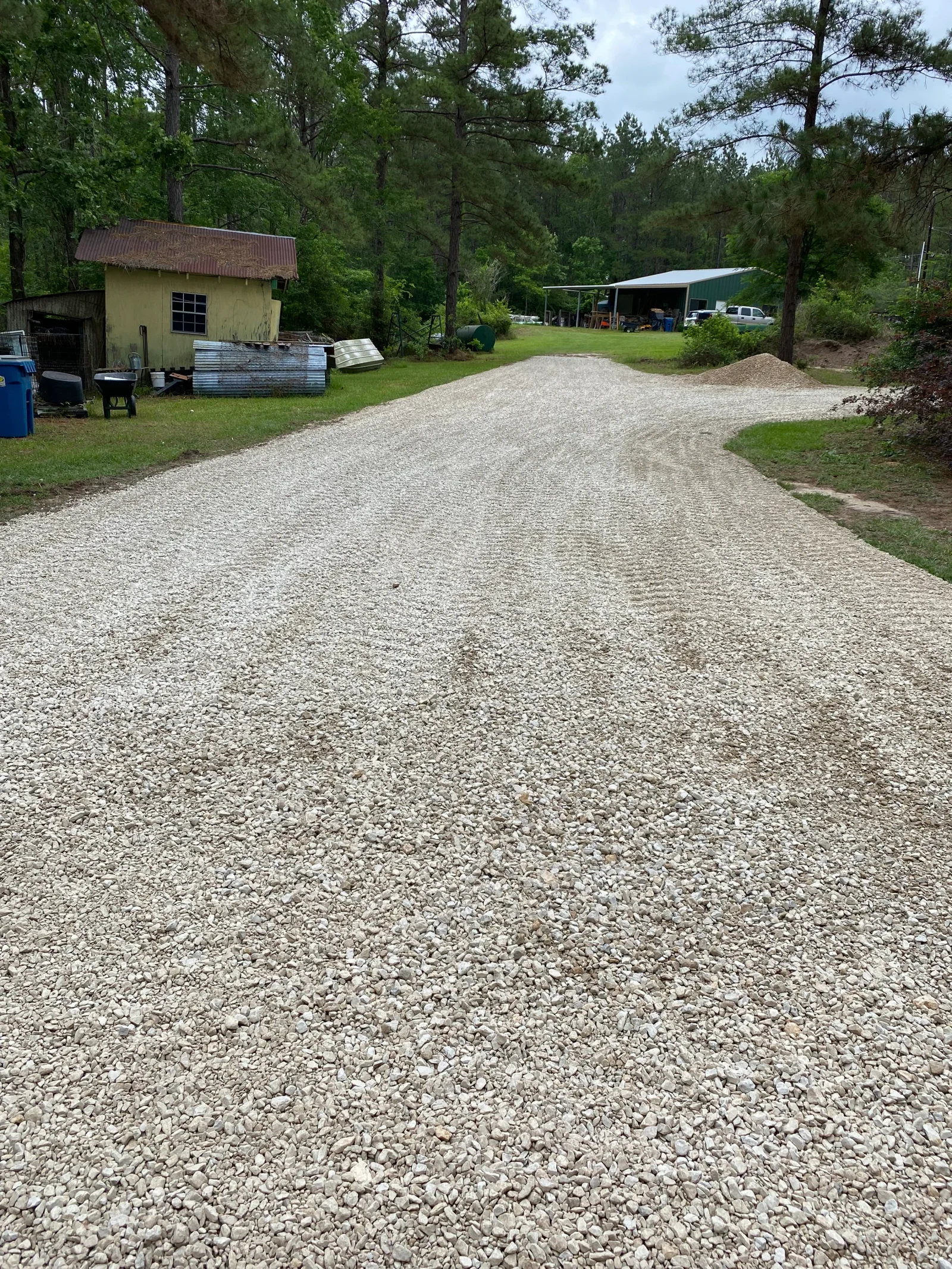 Freshly graded crushed stone driveway with compacted gravel base on rural property