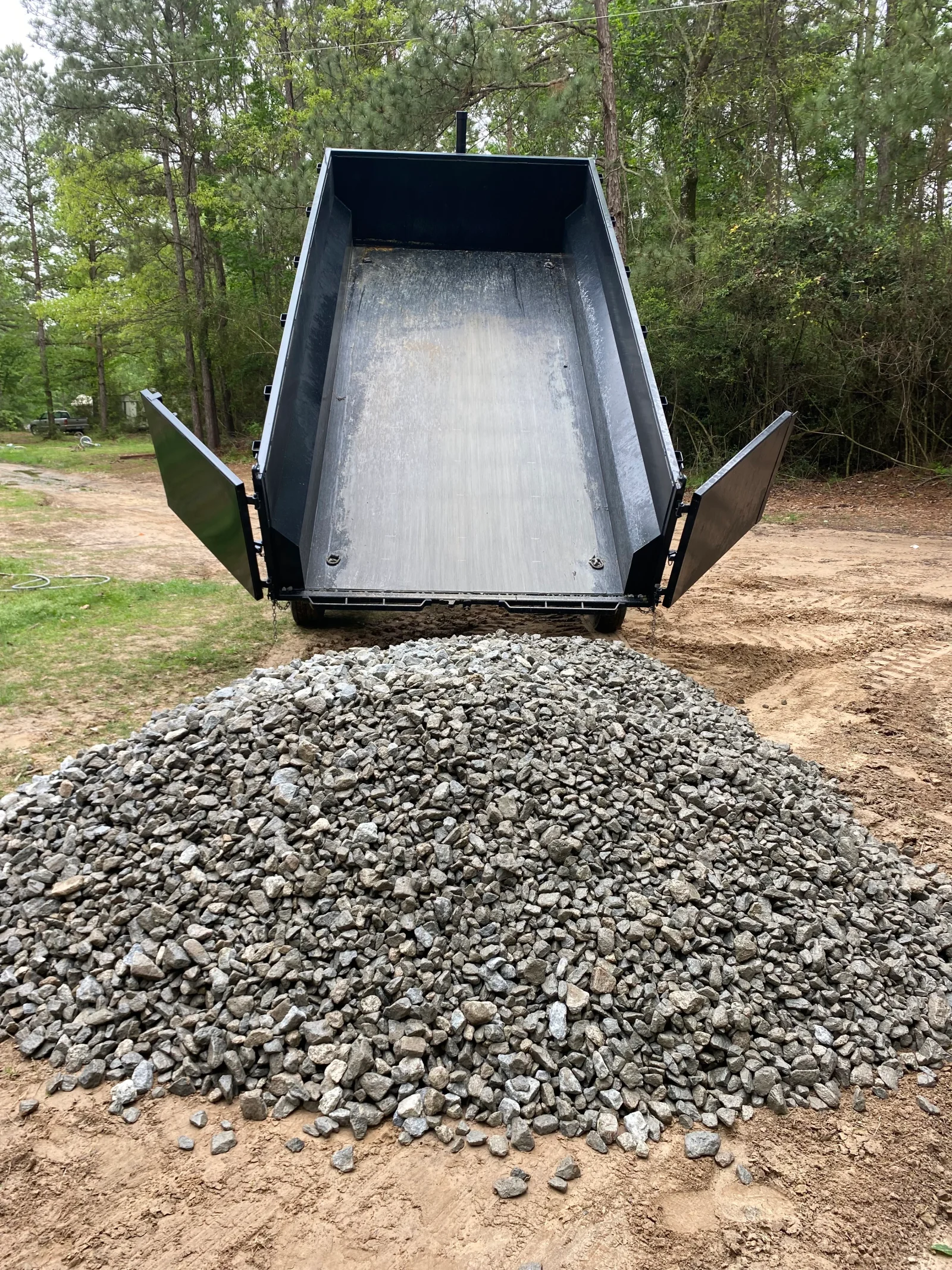 Dump truck with raised bed unloading crushed gravel onto dirt site